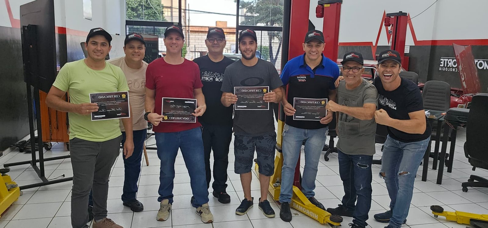 Alunos e professor na oficina MotorForte segurando seus certificados